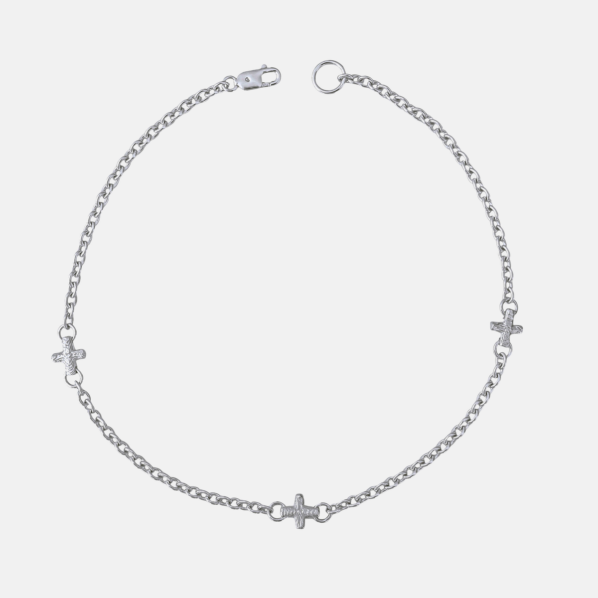 A silver chain anklet featuring three small cross charms and heart charms spaced along the chain, displayed on a light gray background.