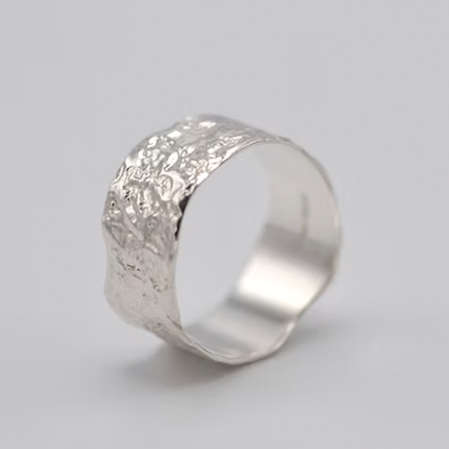 Silver ring with textured surface on a light gray background