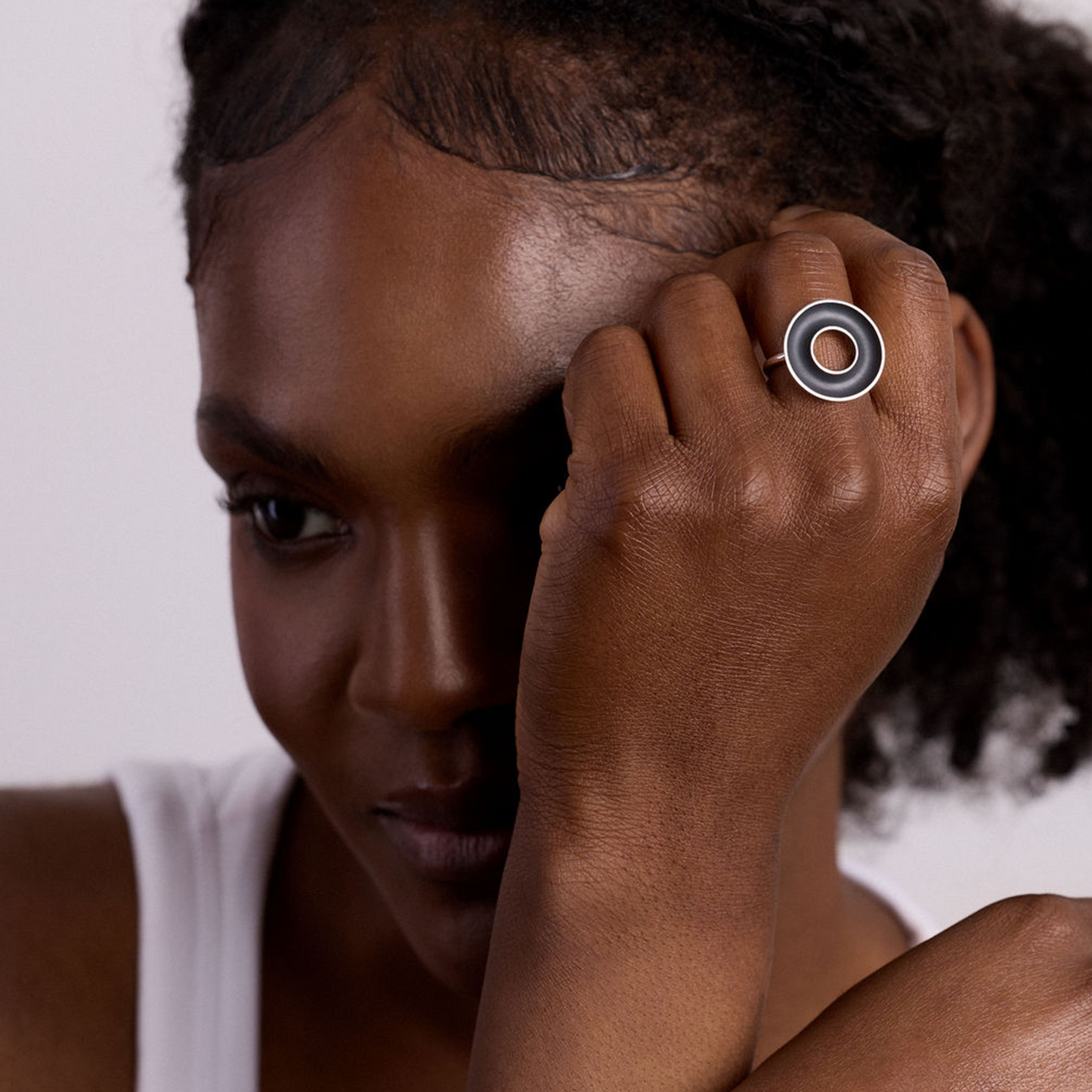 Woman wearing a ring with a circular design on a plain background
