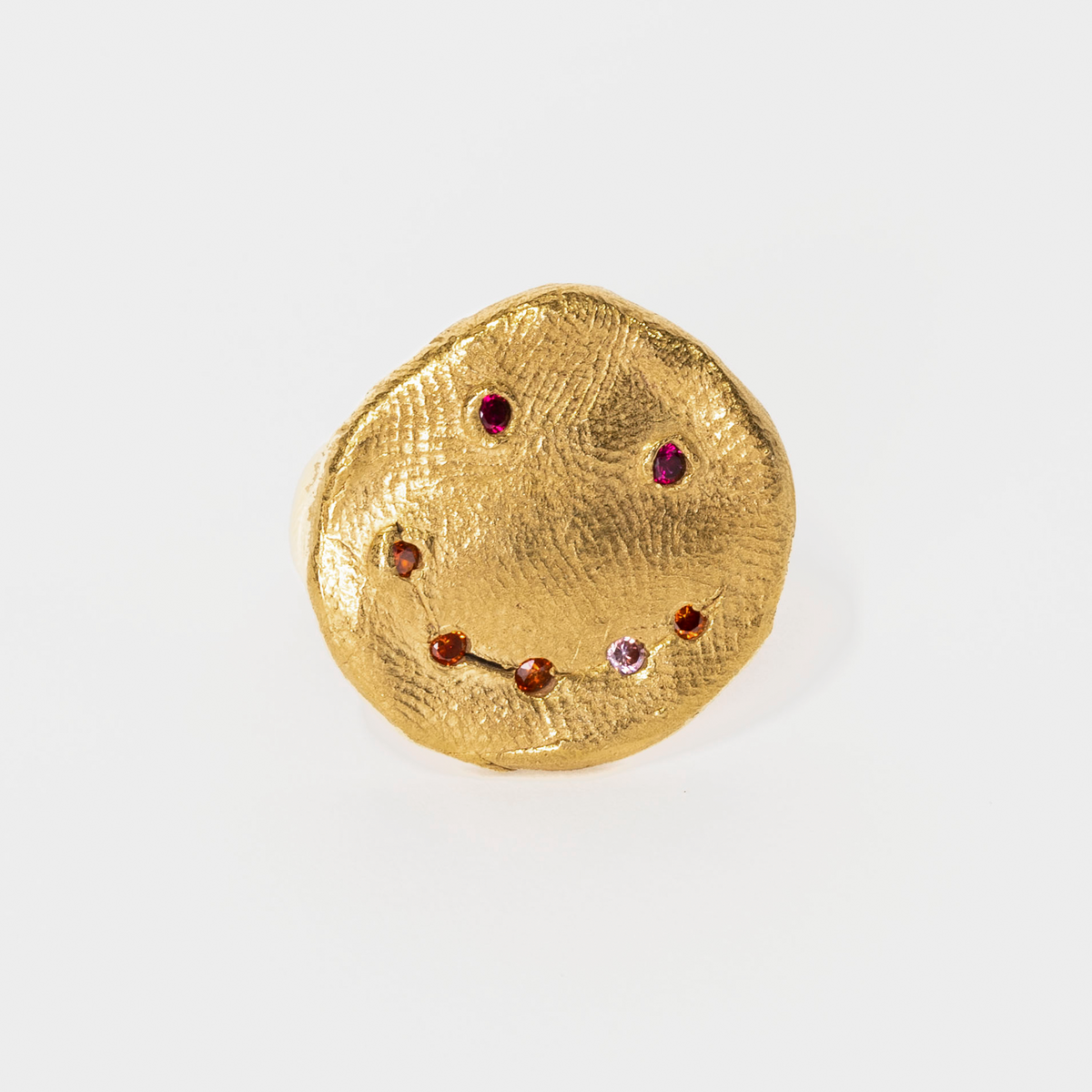 Gold round brooch with embedded gemstones on a white background