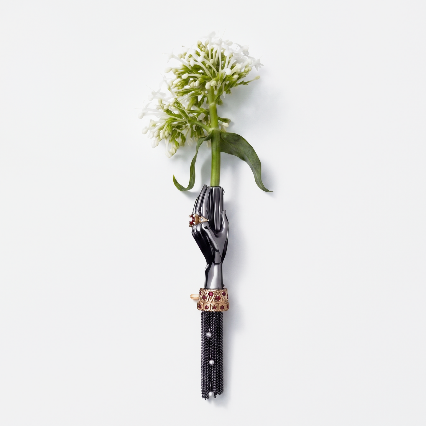 Black hand brooch holding white flower with gold and ruby details, luxury designer statement jewellery