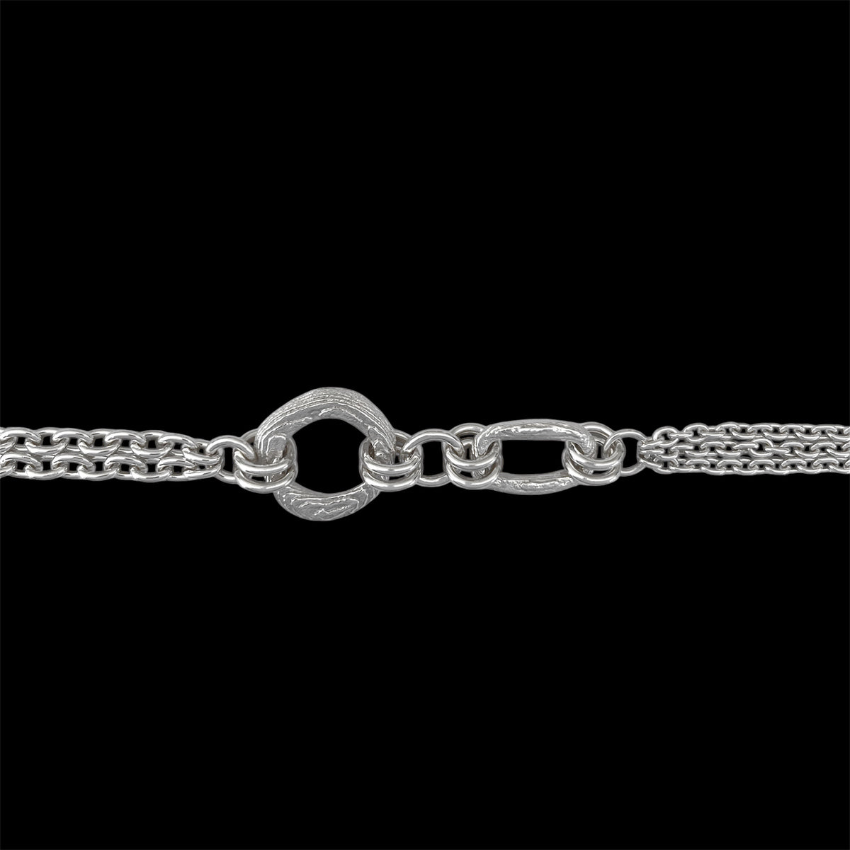 A close-up of a silver-toned chain necklace featuring a distinctive textured heart-shaped clasp connected to elongated oval links, set against a solid black background.