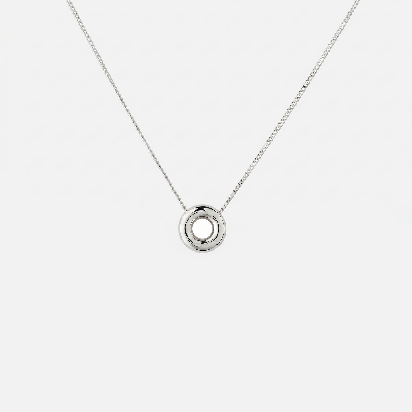 Handmade Monad Mini Sterling Silver Necklace featuring a polished 10 mm torus pendant on a fine sterling silver curb chain. Contemporary minimalist jewellery handcrafted in Glasgow.