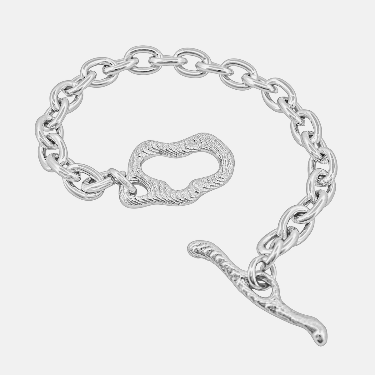 A silver chain bracelet with a textured toggle clasp and a dangling curved charm, shown on a plain white background.