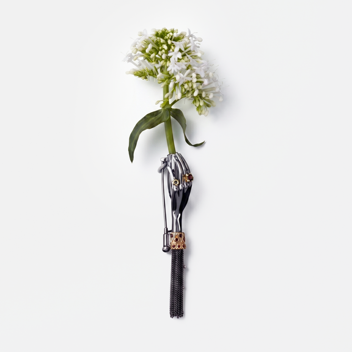 Artistic black hand brooch holding white flower with gemstone details, high-end statement jewellery