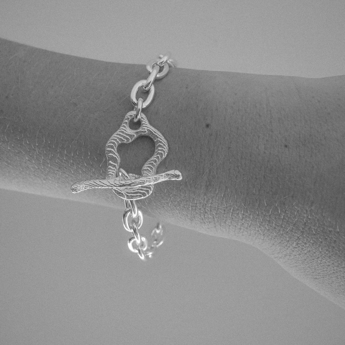 Silver bracelet with a unique design worn on a wrist against a neutral background