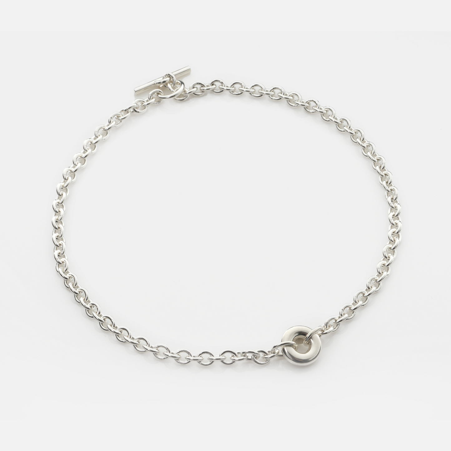 Handmade sterling silver Monad Chain Necklace featuring a polished sculptural torus pendant, chunky cable chain and T-bar clasp. Contemporary designer jewellery handcrafted in Glasgow.