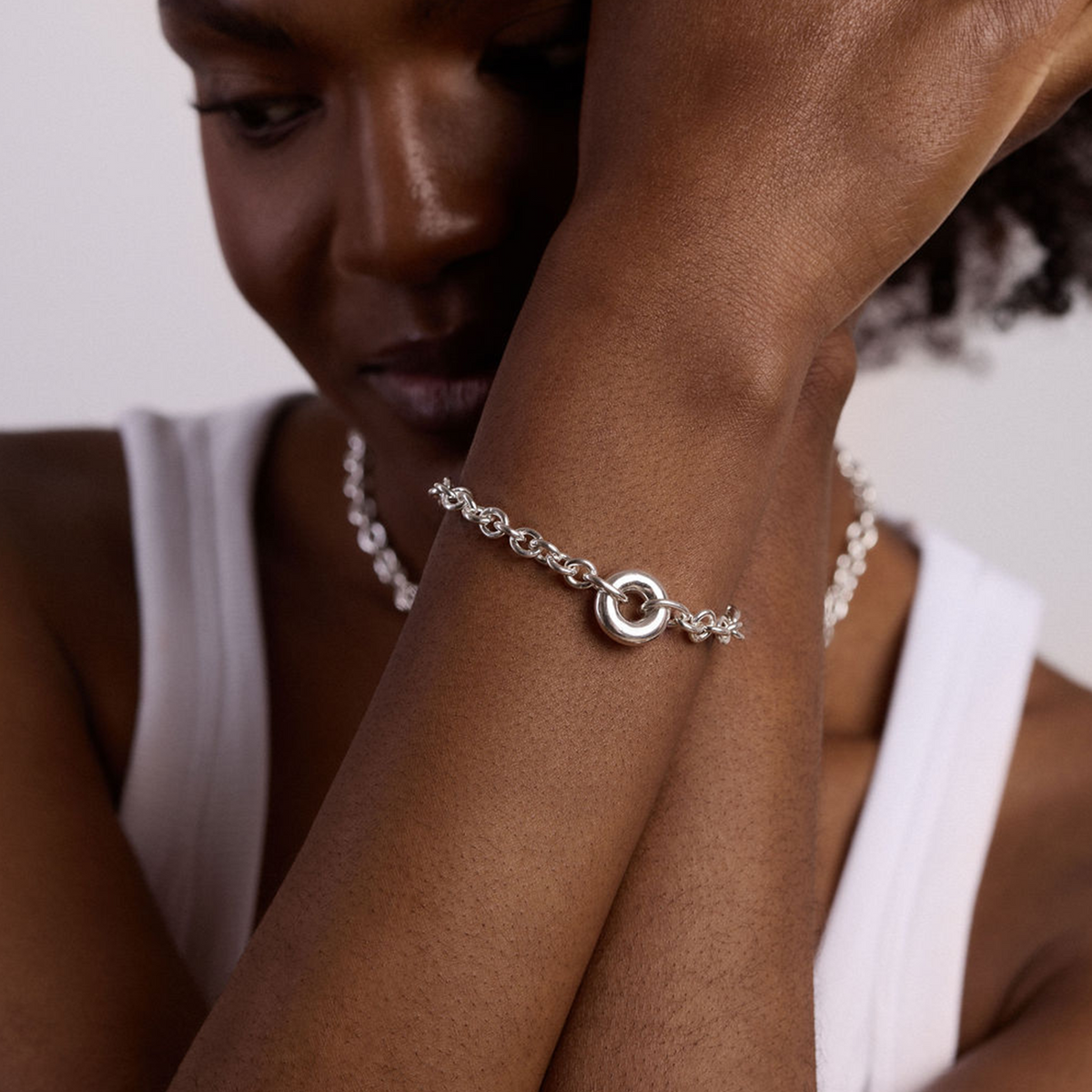 Model wearing the handmade sterling silver Monad Chain Bracelet with a sculptural torus link and chunky chain. Contemporary artisan jewellery for everyday luxury.