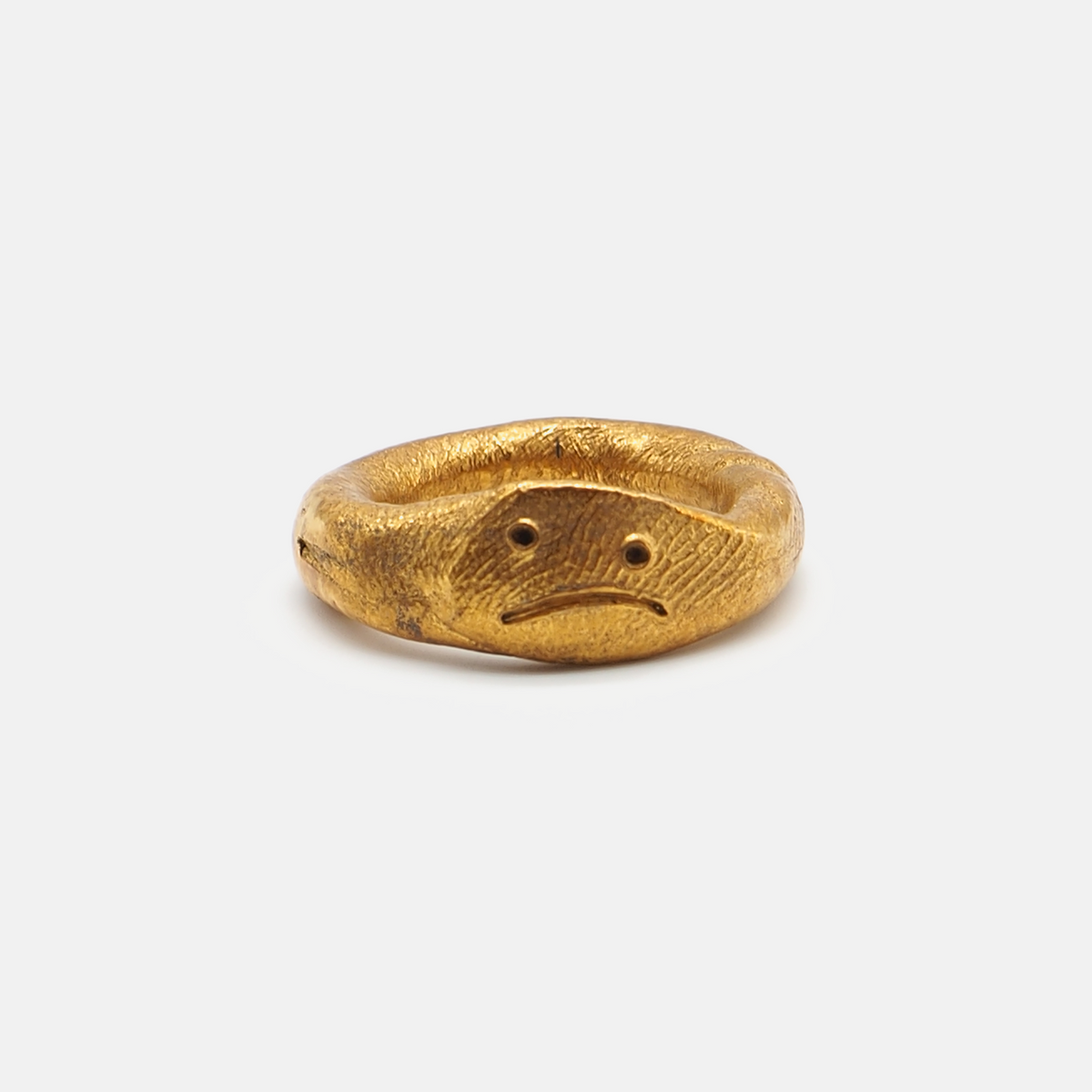 Gold ring with a face design on a white background