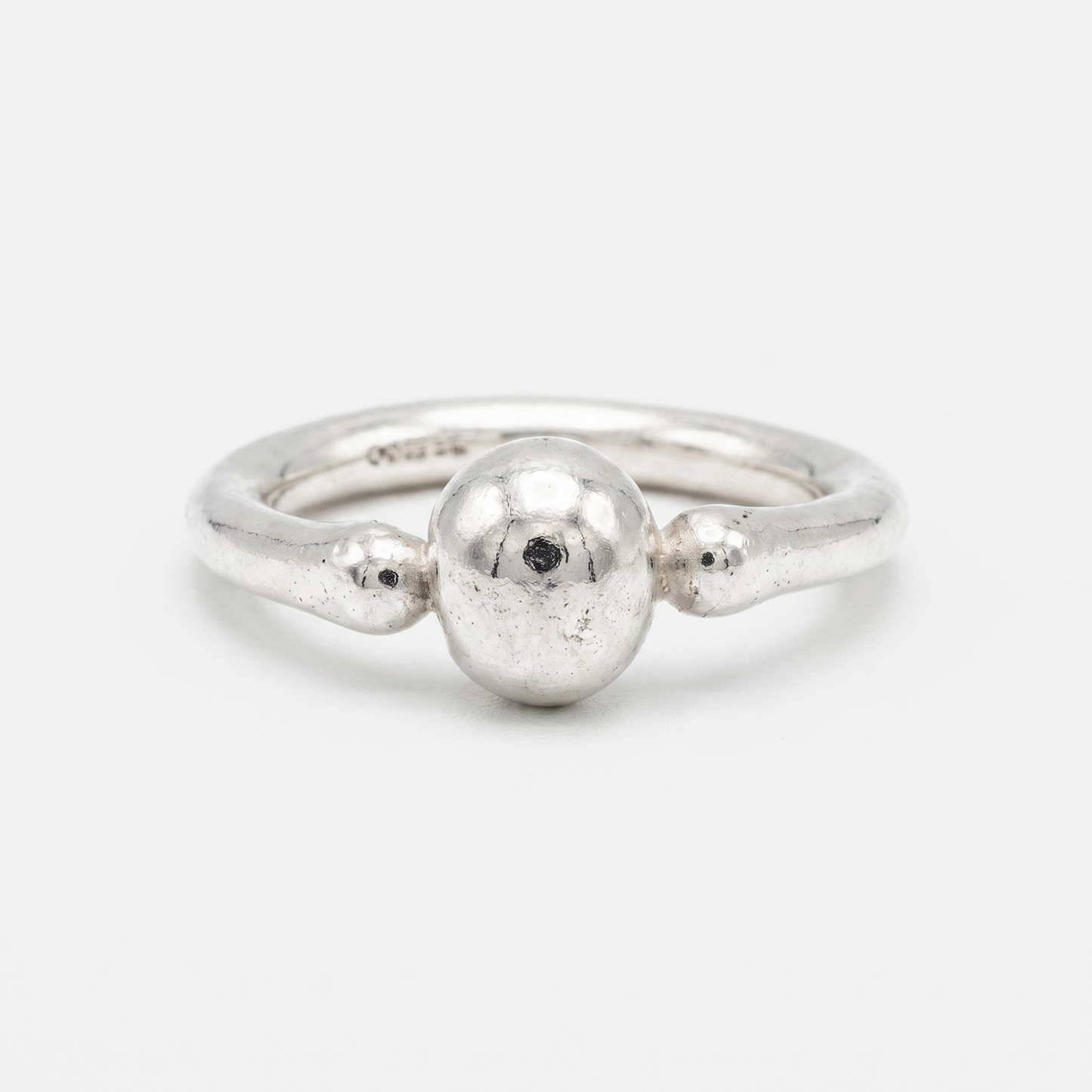 A sterling silver ring with a textured, organic-shaped band and a central polished oval bead, photographed on a clean white background.