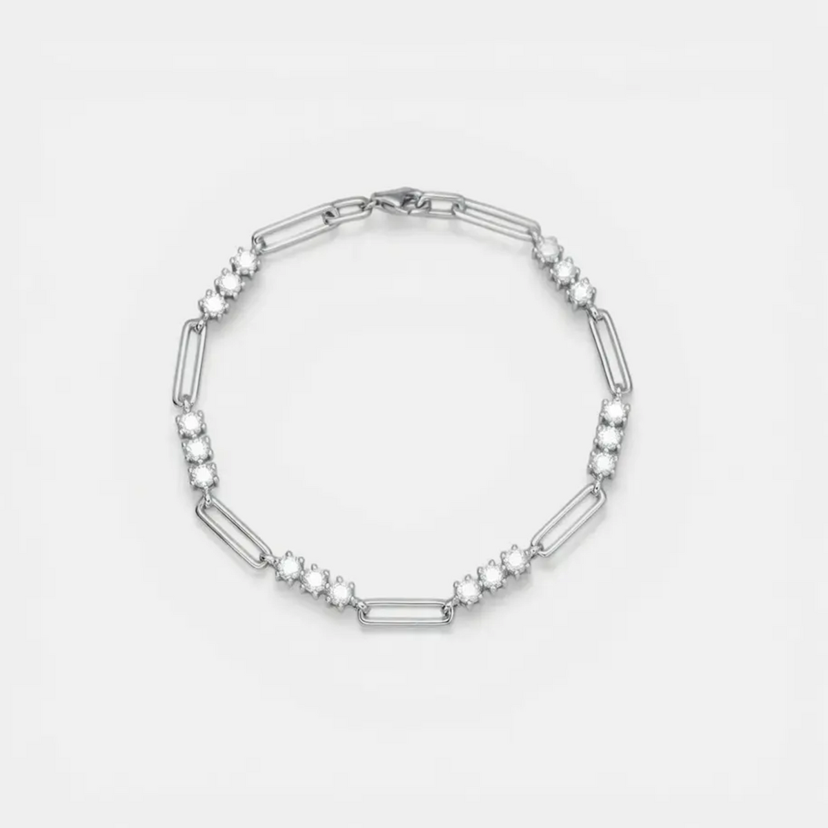 A silver-toned link bracelet featuring alternating elongated oval links and clusters of small round clear stones, displayed on a clean white background.