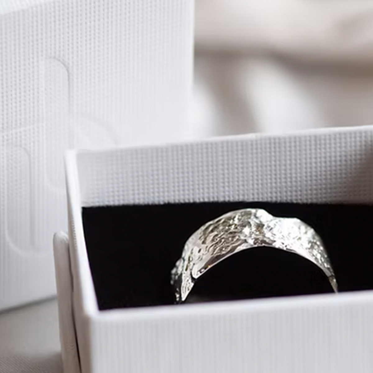 Silver ring with a black background inside a white box