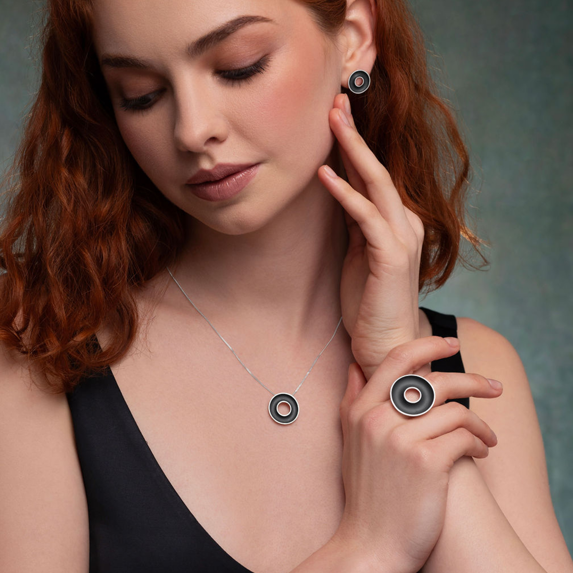 Woman wearing a necklace and earrings, holding one earring with her hand.