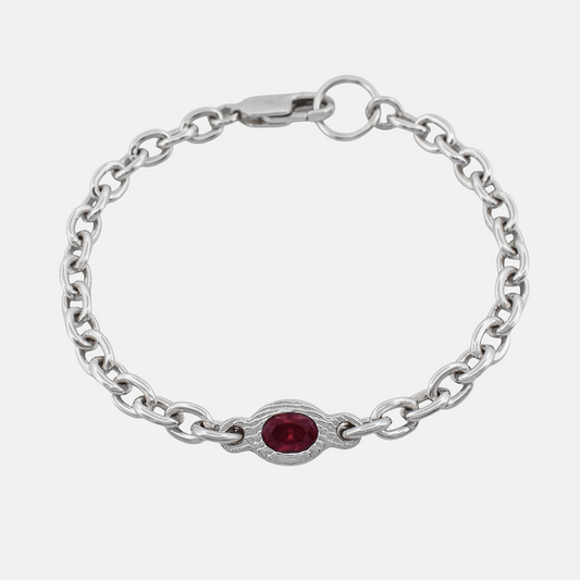 A silver chain bracelet featuring a central oval-cut red gemstone in a decorative silver bezel setting, shown on a light gray background.