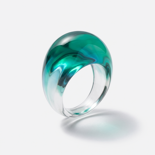 A thick, dome-shaped clear glass ring with a marbled swirl of vibrant green and teal, shown on a clean white background with a soft shadow underneath.