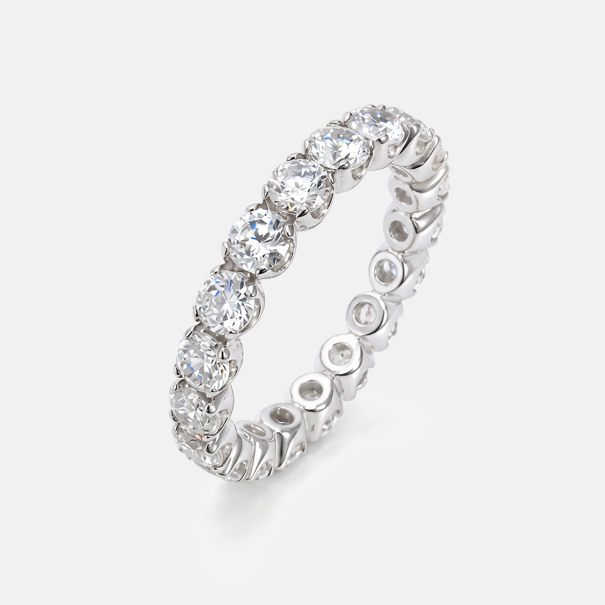 A silver-toned eternity ring featuring a continuous row of round brilliant-cut clear gemstones on a light gray background.