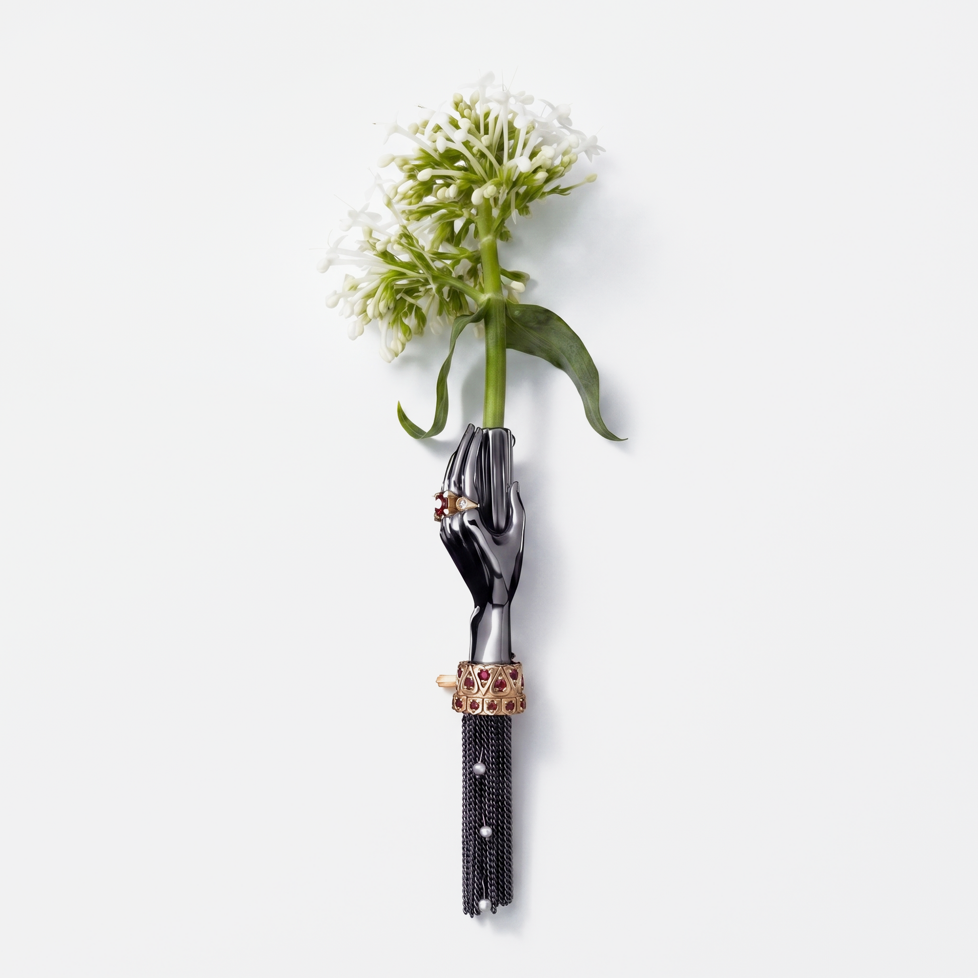 Black hand brooch holding white flower with gold and ruby details, luxury designer statement jewellery