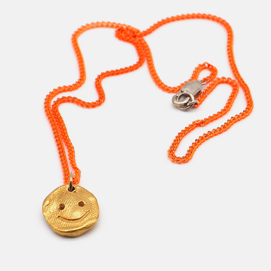Gold face pendant necklace with neon orange chain