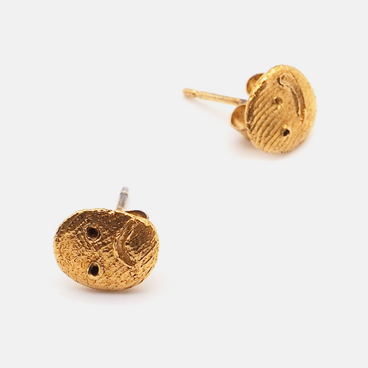 Handcrafted gold face stud earrings on white background