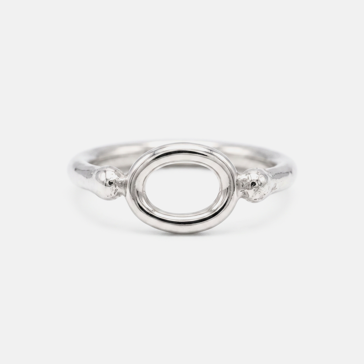 A silver ring featuring a polished oval center with textured, beaded details on the sides, set against a plain light gray background.