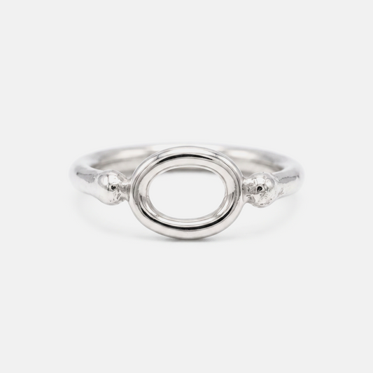 A silver ring featuring a polished oval center with textured, beaded details on the sides, set against a plain light gray background.