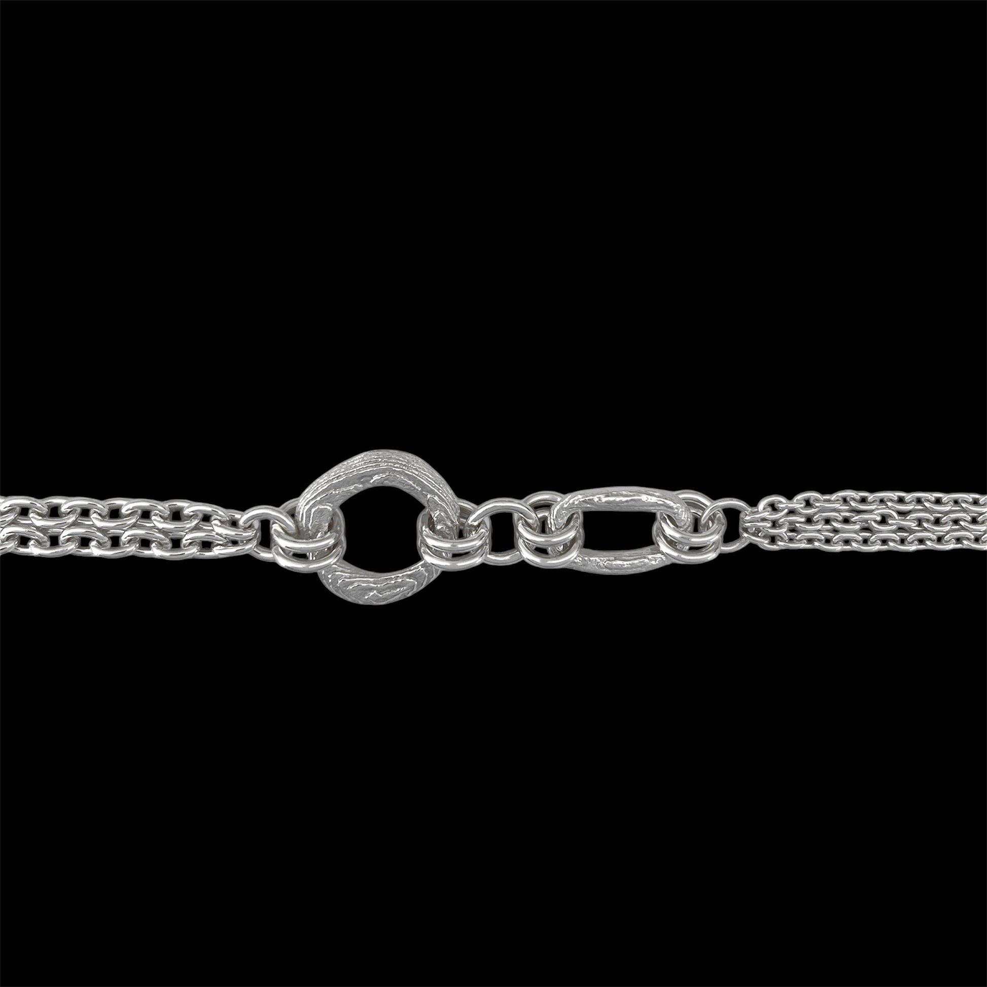 A close-up of a silver-toned chain necklace featuring a distinctive textured heart-shaped clasp connected to elongated oval links, set against a solid black background.