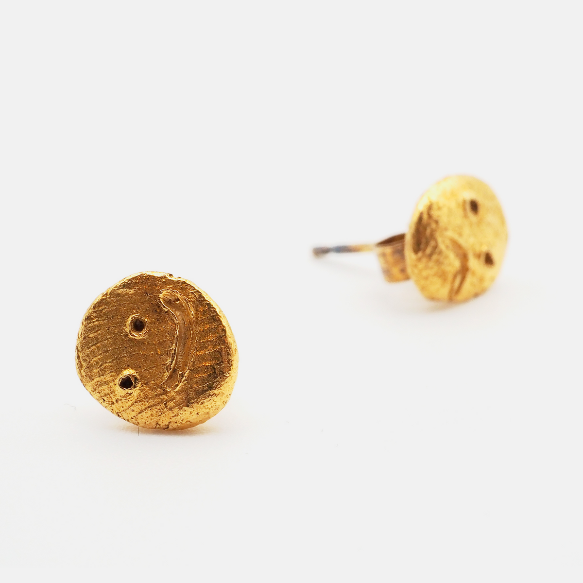 Textured gold face stud earrings close-up

