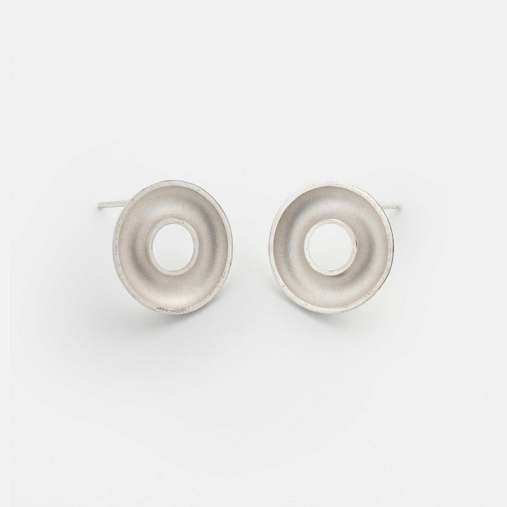 Handmade Orbis Small Sterling Silver Stud Earrings featuring a sculptural concave torus design with polished finish. Contemporary minimalist jewellery handcrafted in Glasgow.