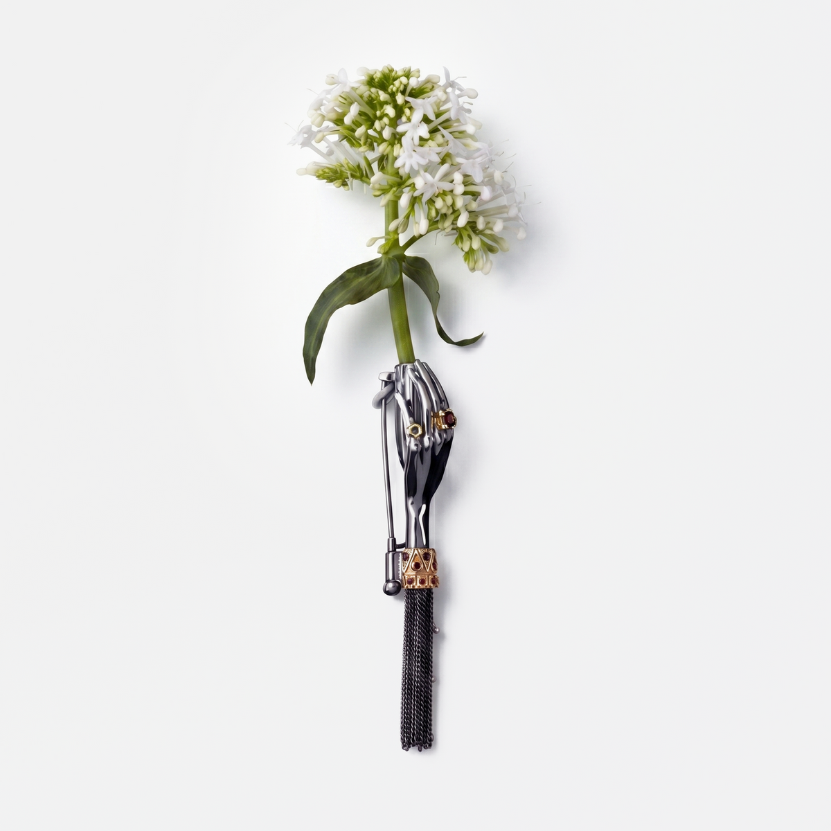 Artistic black hand brooch holding white flower with gemstone details, high-end statement jewellery