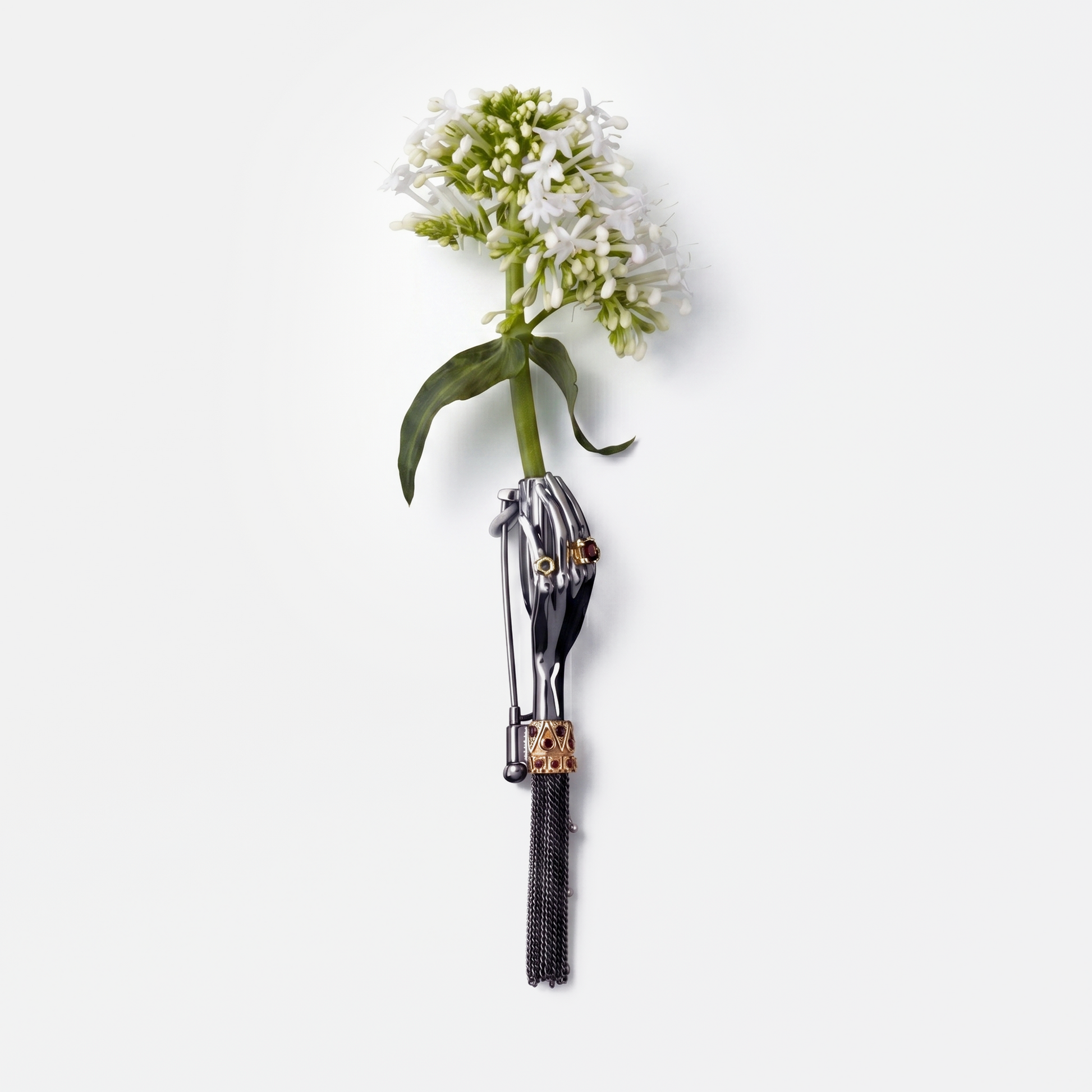Artistic black hand brooch holding white flower with gemstone details, high-end statement jewellery