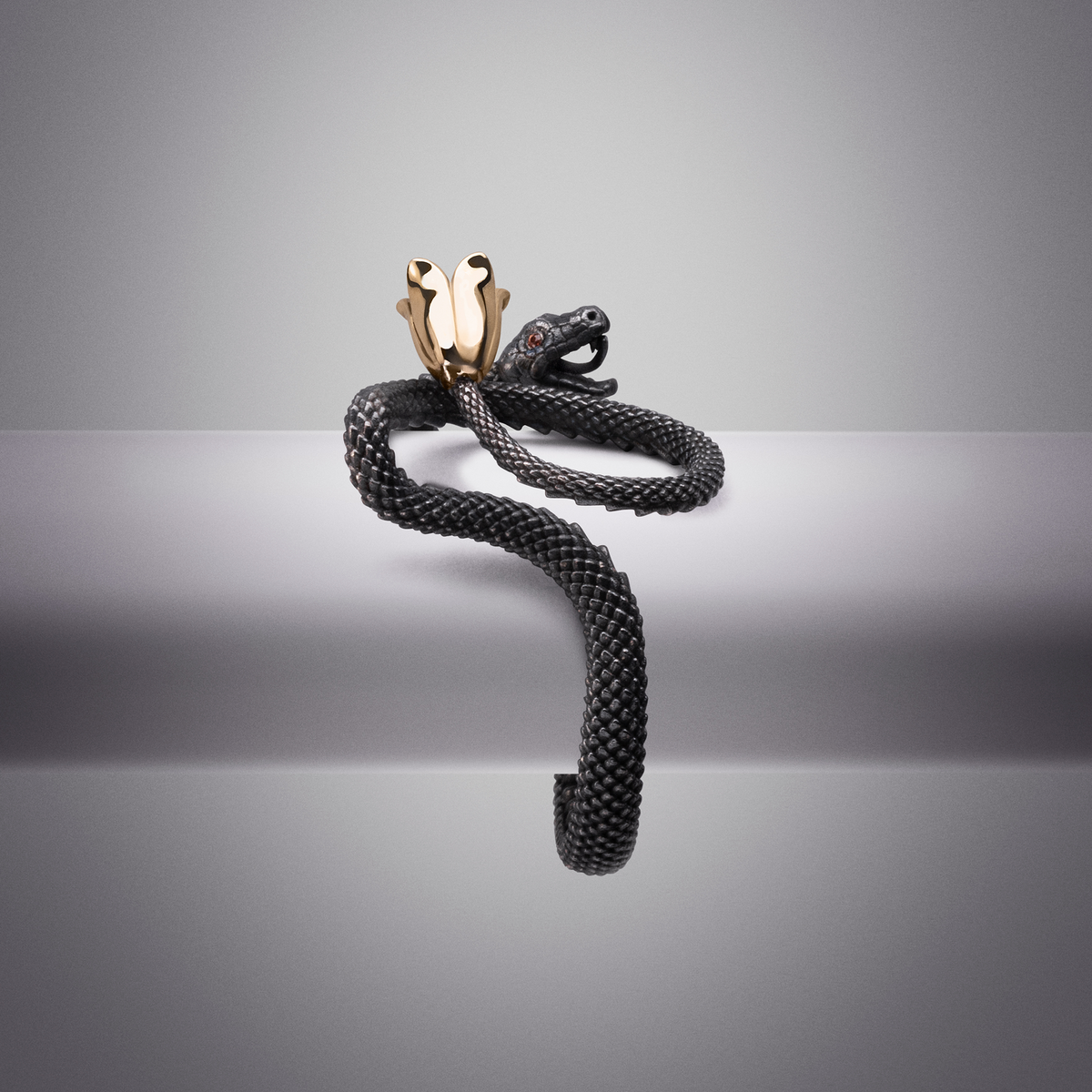 Bold snake wrap ring in black metal with gold accent, contemporary designer jewellery piece