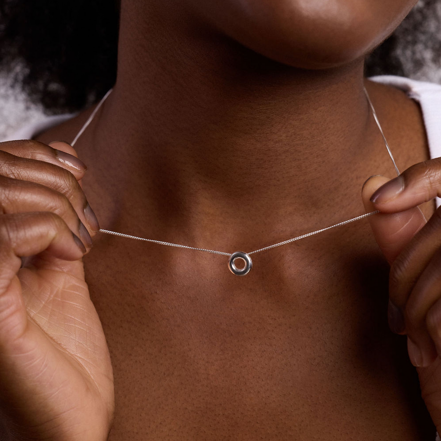 Close-up of the handcrafted Monad Mini Sterling Silver Necklace showcasing the polished torus pendant and fine sterling silver chain.