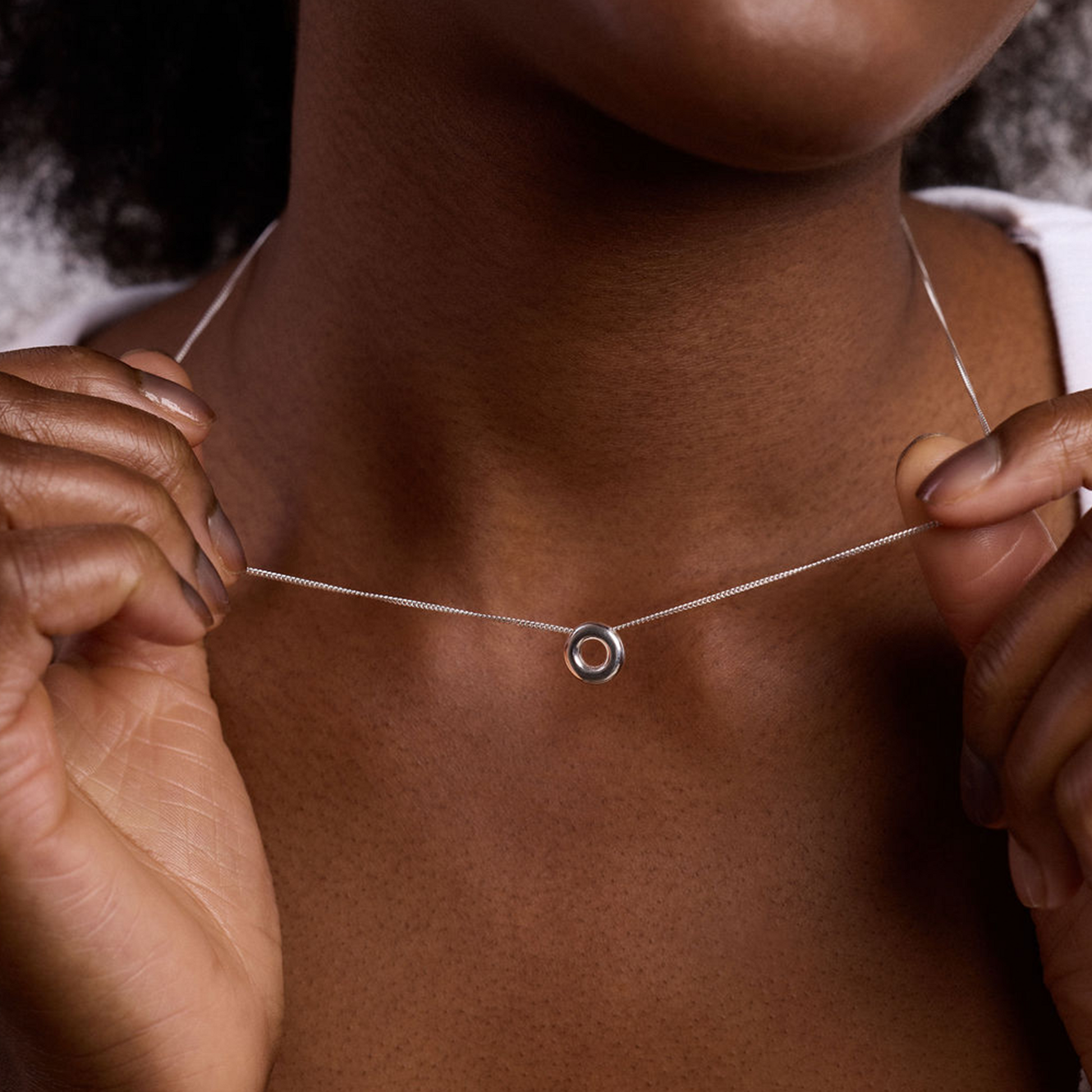 Close-up of the handcrafted Monad Mini Sterling Silver Necklace showcasing the polished torus pendant and fine sterling silver chain.