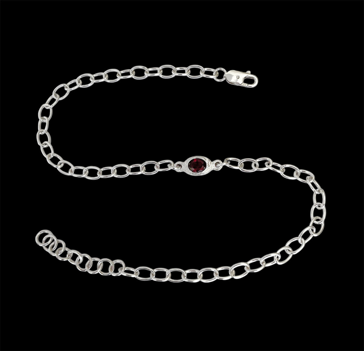Silver chain bracelet with a red gemstone on a black background