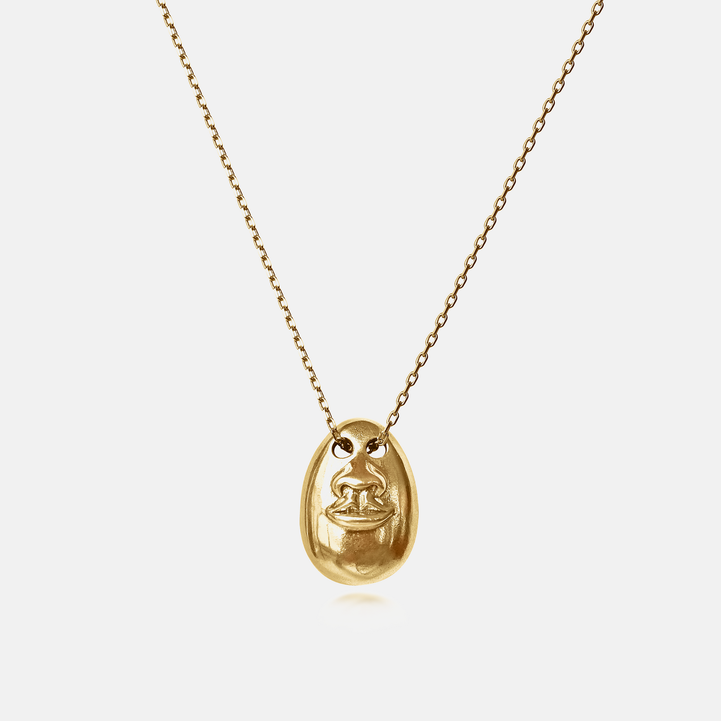 See No Evil Pendant Necklace in gold featuring a sculptural face motif on a delicate chain against a white background.
