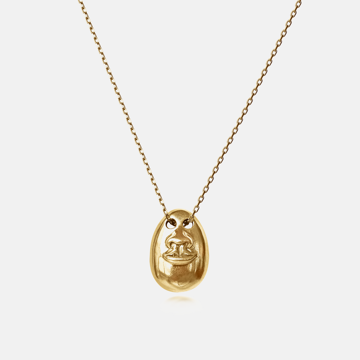See No Evil Pendant Necklace in gold featuring a sculptural face motif on a delicate chain against a white background.
