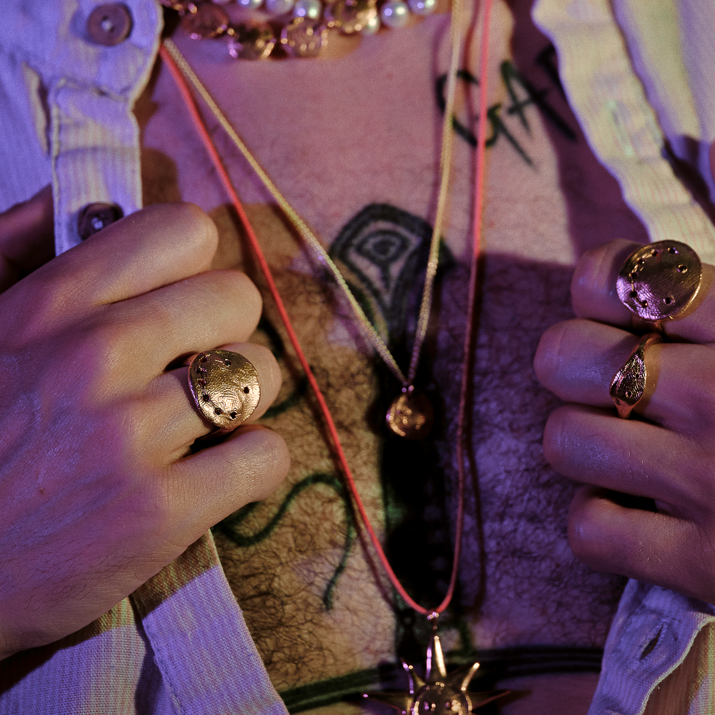 Close-up of hands wearing gold rings with a textured background