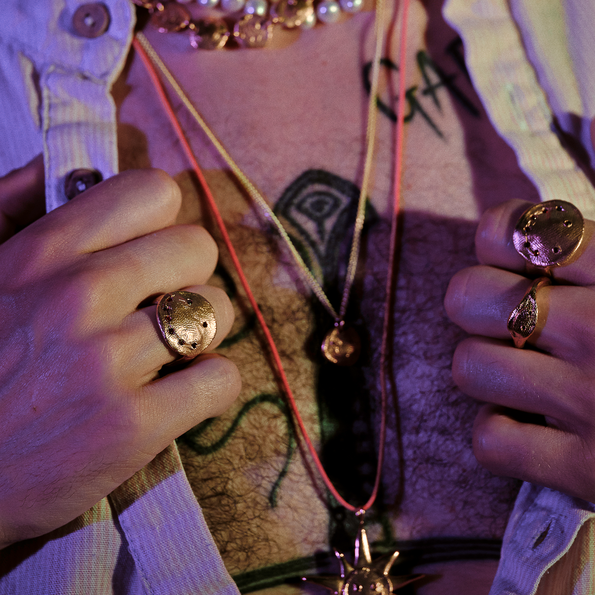 Close-up of hands wearing gold rings with a textured background