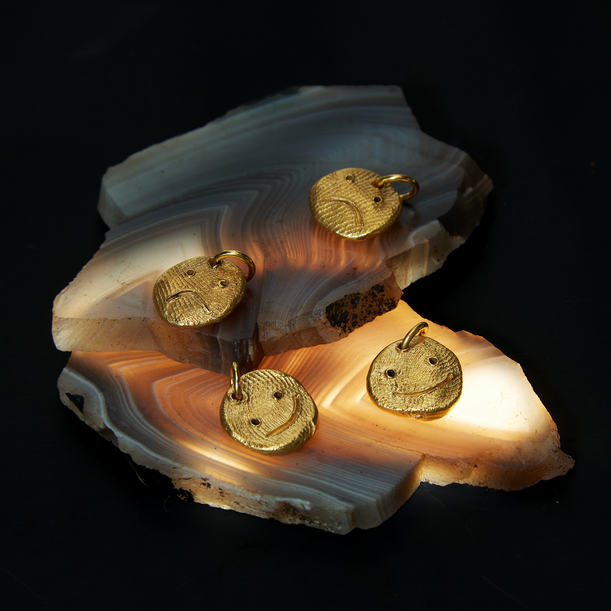 Gold sculptural pendants displayed on natural stone surface
