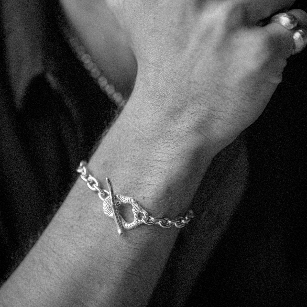 Silver bracelet on a wrist with a dark background