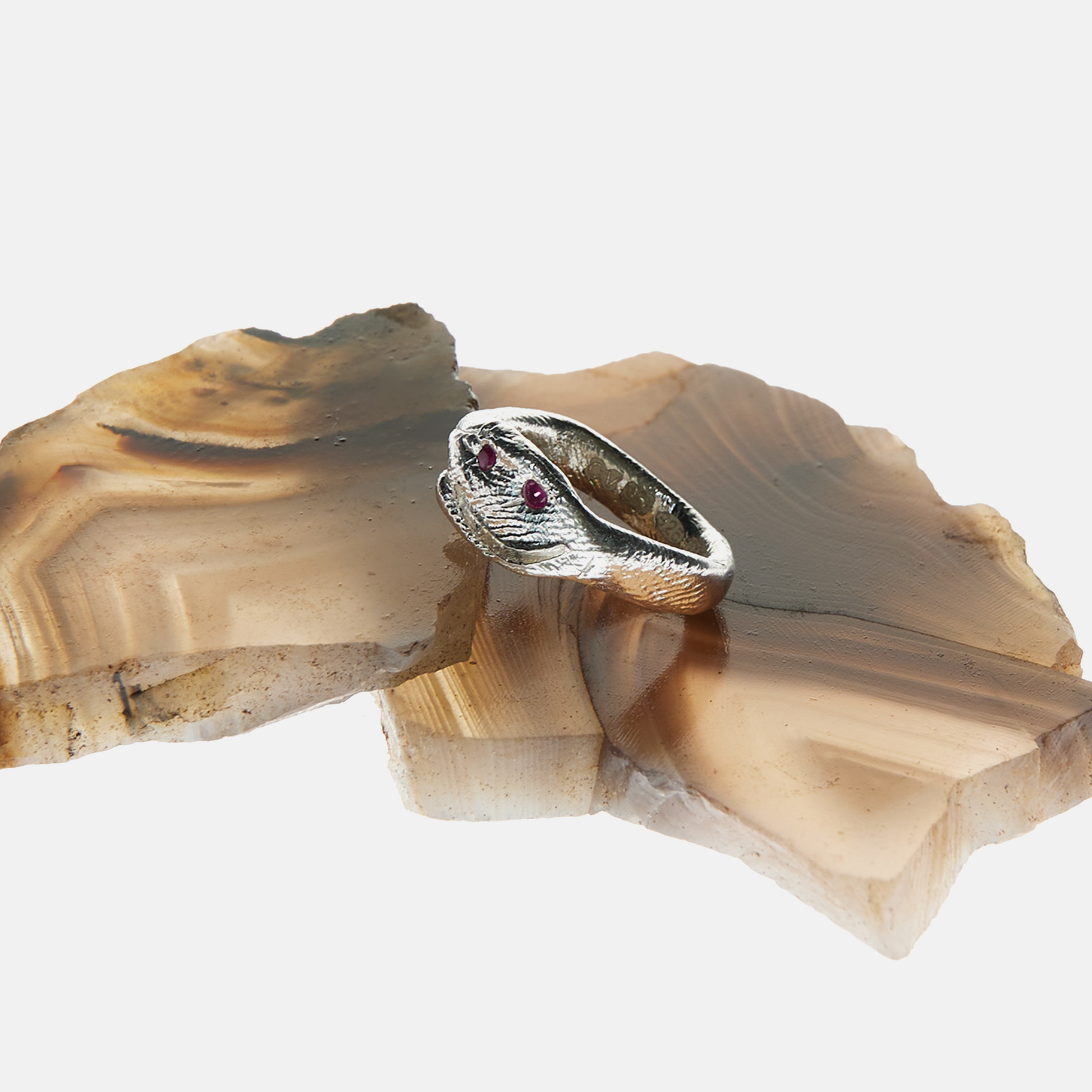 Silver ring with a red gemstone on a piece of agate stone