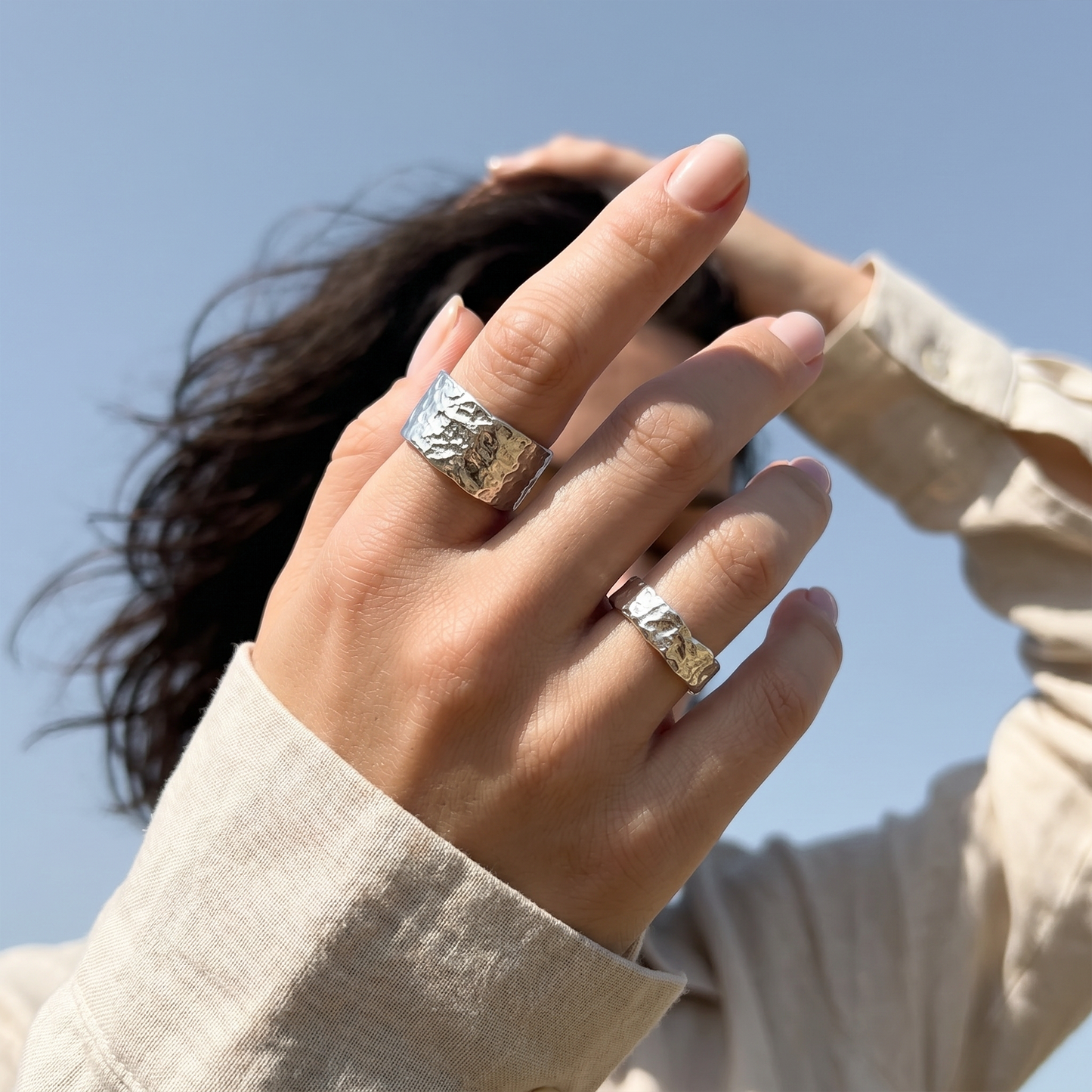 Hand wearing two silver rings with a blurred background