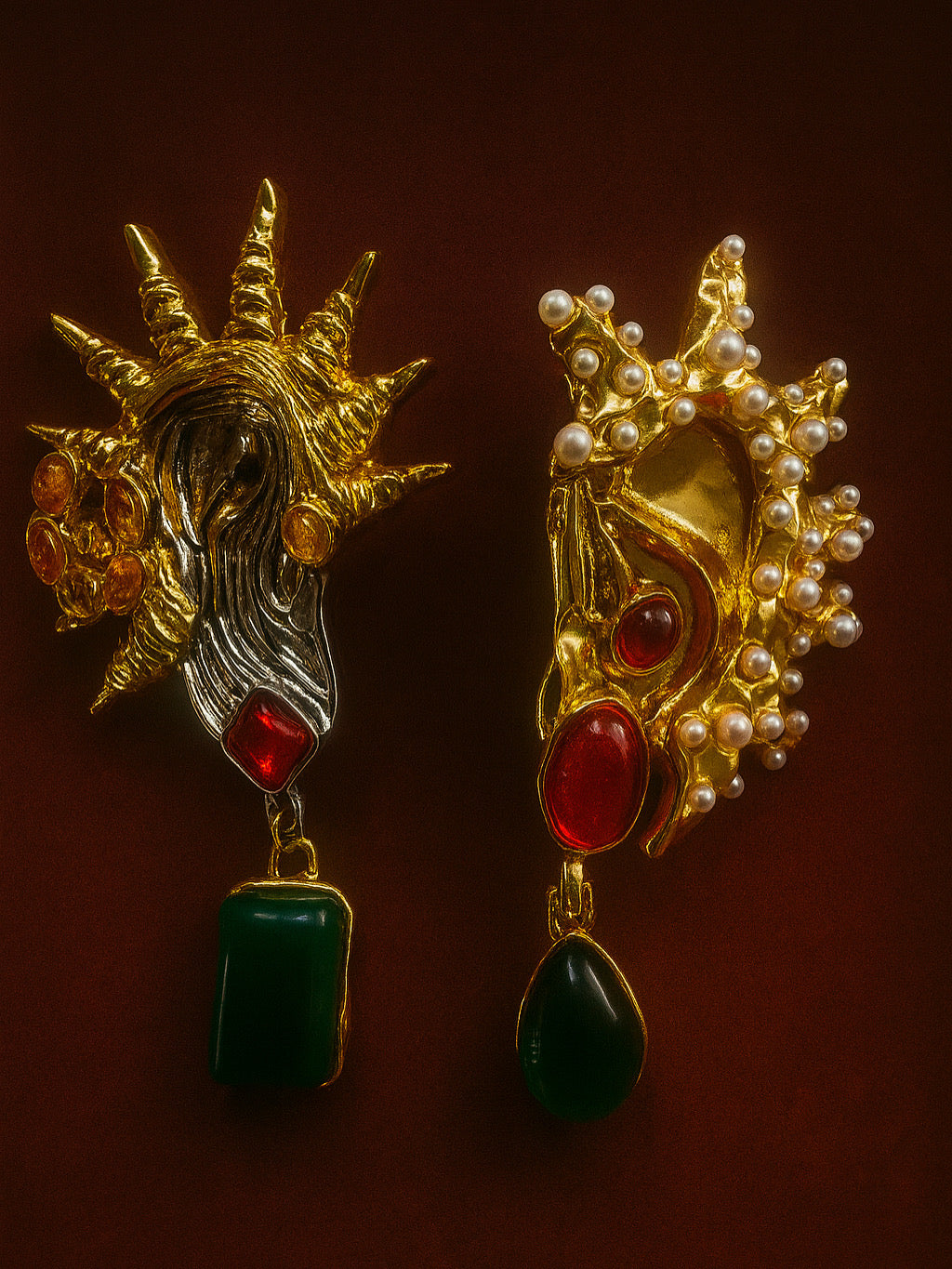 Pair of ornate earrings with gold, red, and green stones on a dark background