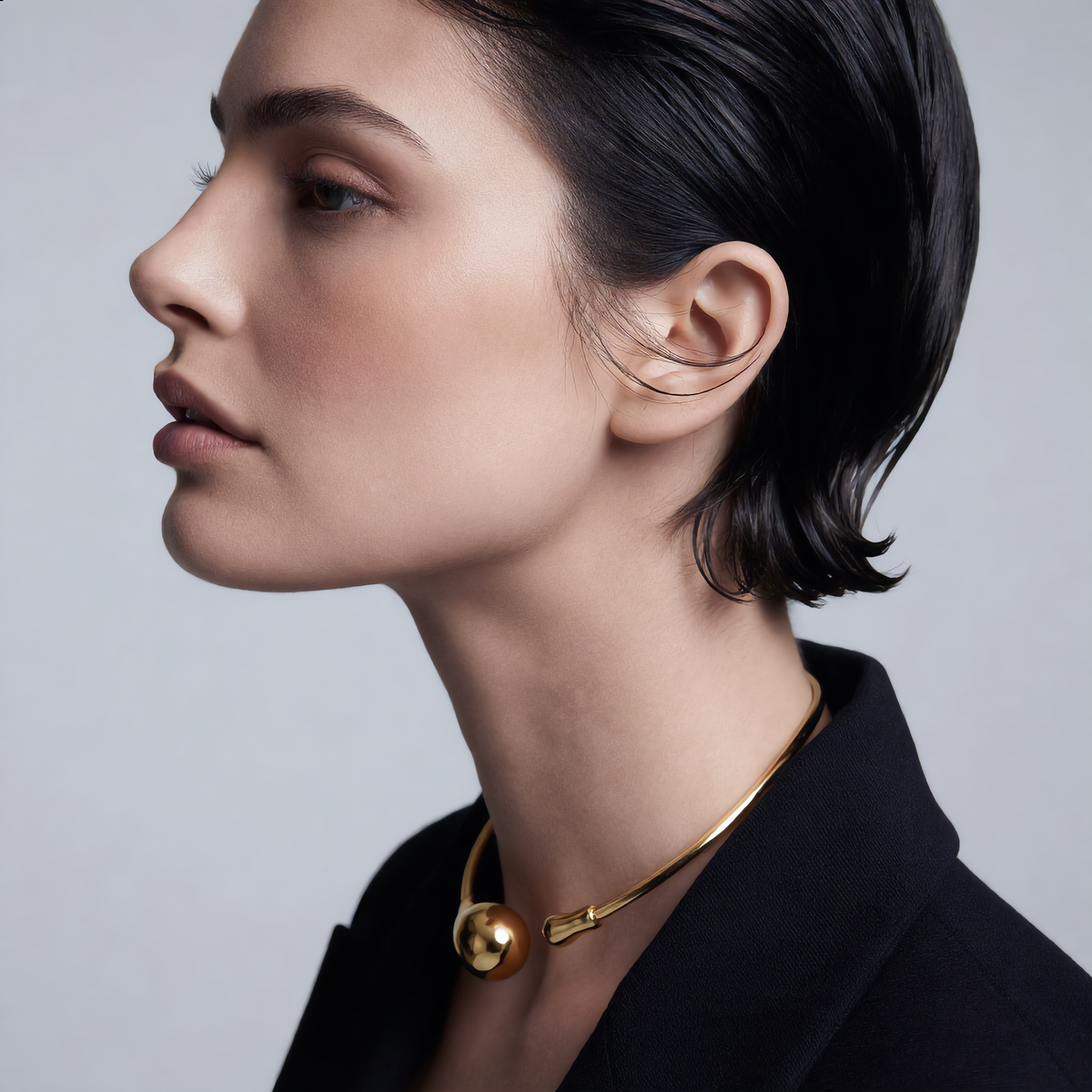 Woman wearing a gold necklace against a gray background