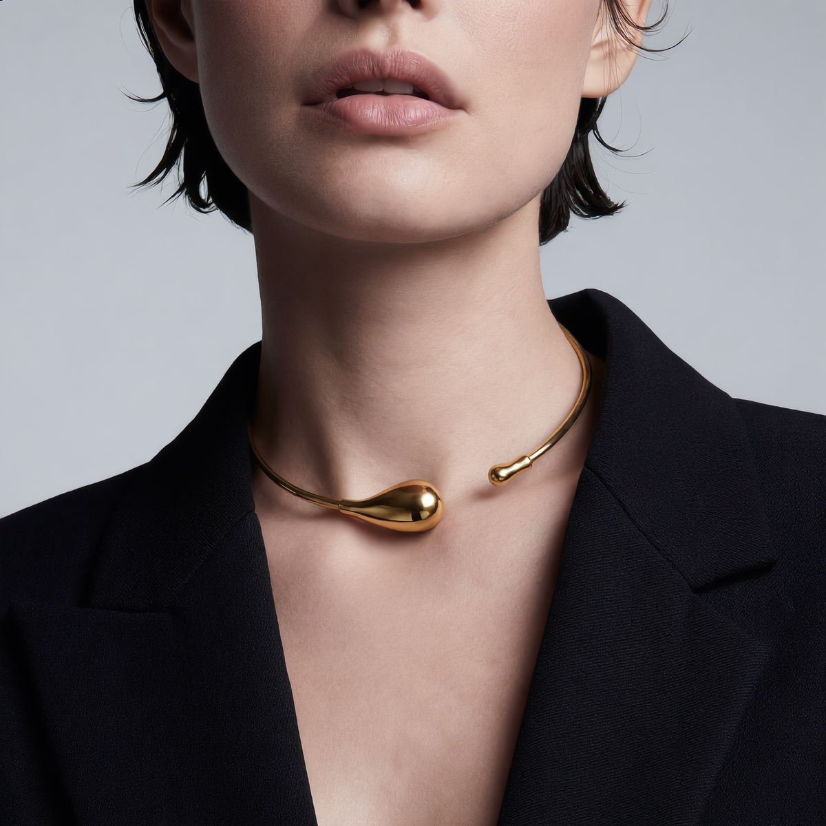Gold necklace worn by a model against a neutral background