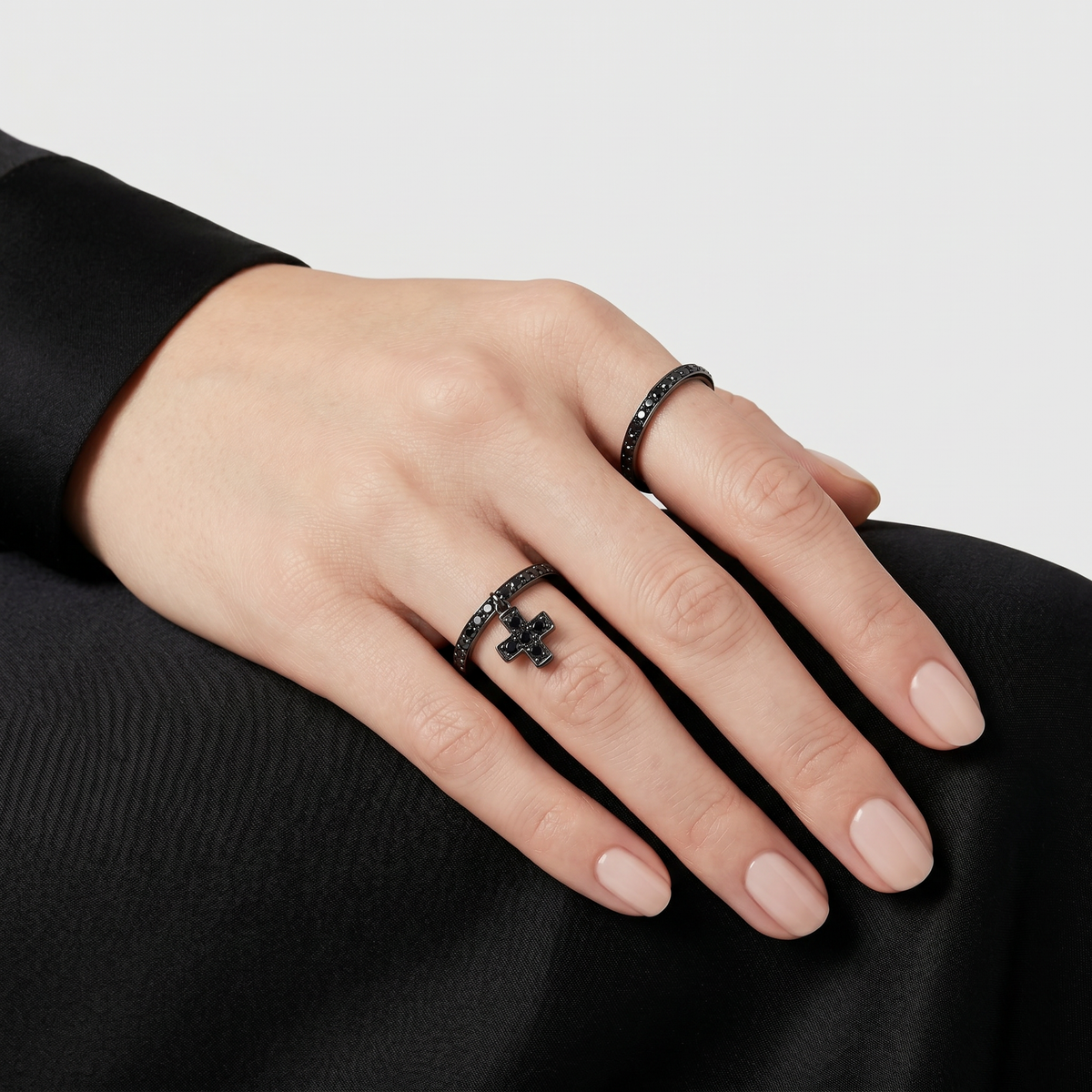 Woman wearing black diamond rings in blackened 18k gold by Sybarite Jewellery, stackable designer rings with cross detail, modern luxury jewellery styling