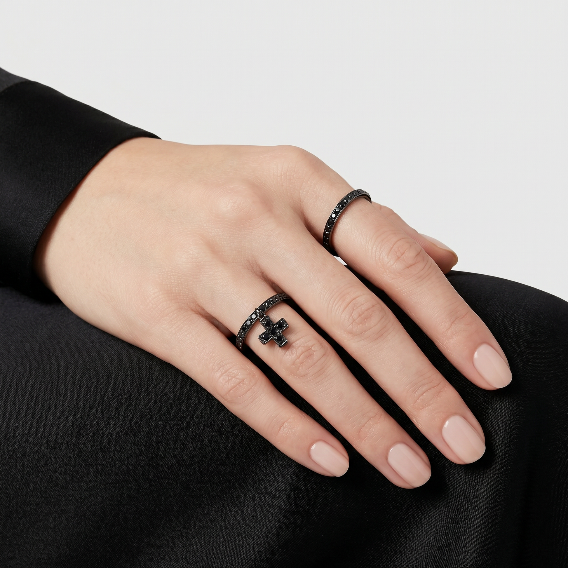 Woman wearing black diamond rings in blackened 18k gold by Sybarite Jewellery, stackable designer rings with cross detail, modern luxury jewellery styling