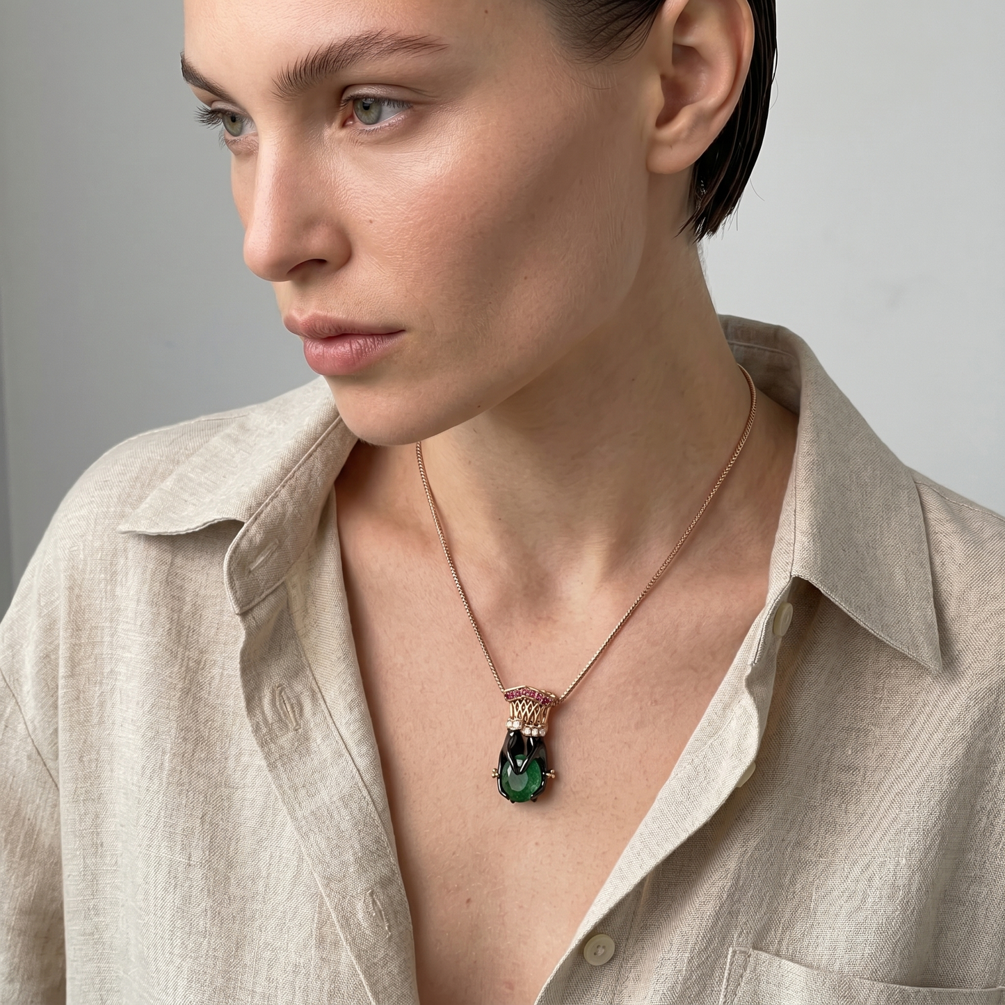 Woman wearing a necklace with a green pendant against a neutral background