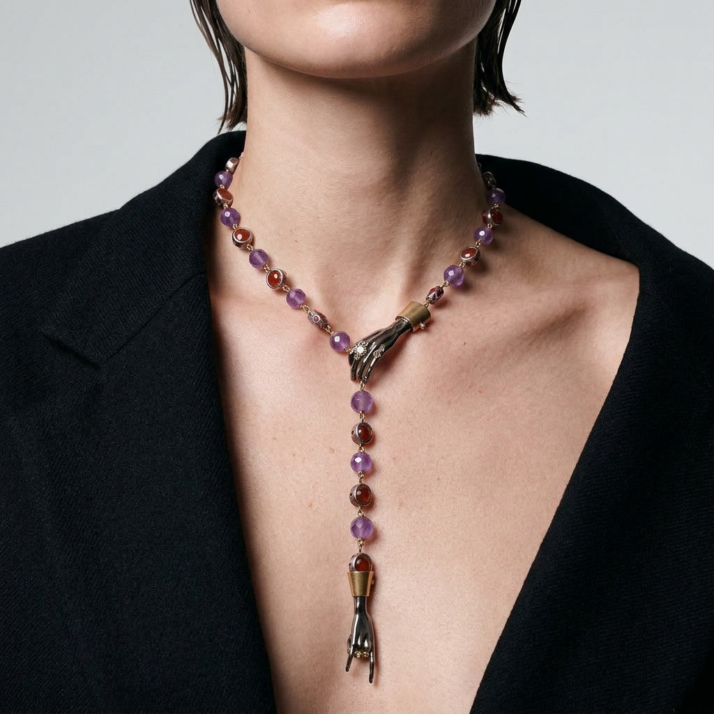 Woman wearing luxury hand pendant necklace with amethyst and red gemstones, statement designer jewellery, elegant styling with black blazer