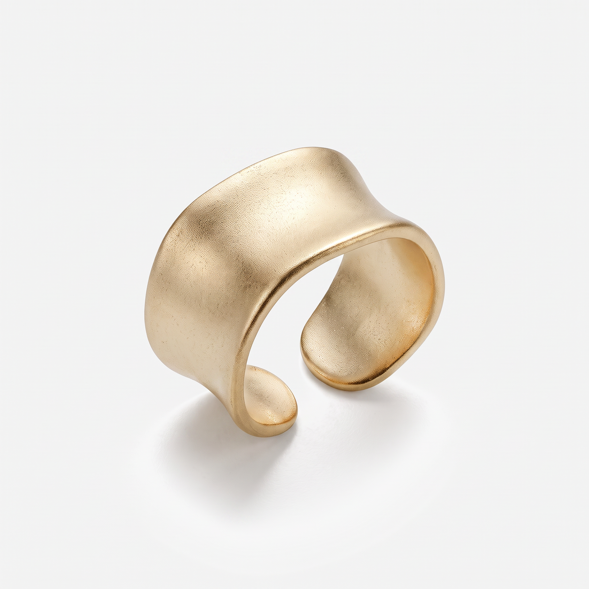 A wide, open cuff ring with a smooth, organic wavy shape in a matte gold finish, photographed on a clean white background with a soft shadow.